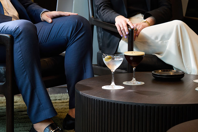 man and woman sitting with 2 cocktails